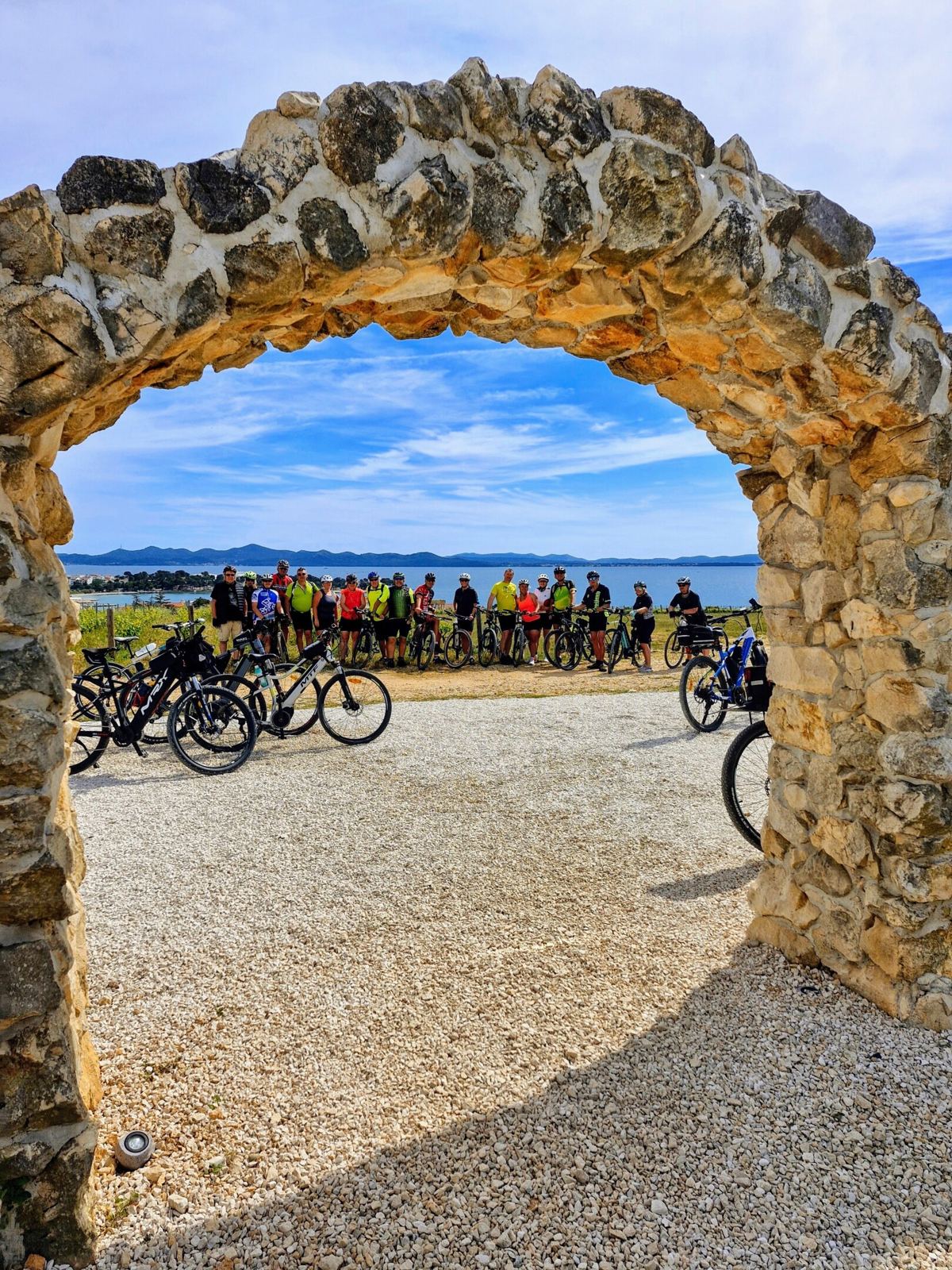 Cyklisté pod kamenným obloukem